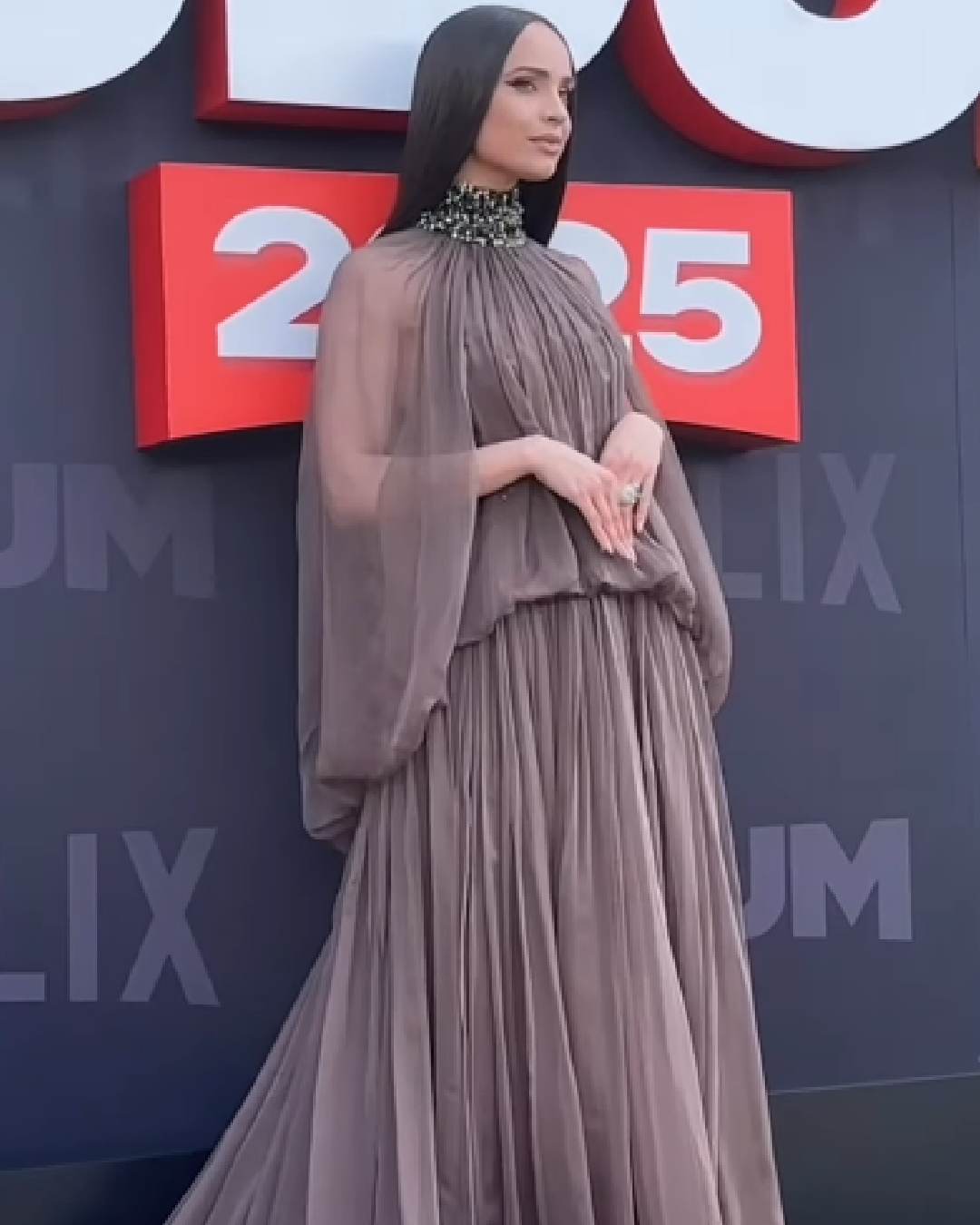 Tudum 2025 was hosted by actress-singer Sofia Carson, who looked gorgeous in a pleated mauve gown with a floor-sweeping train. 