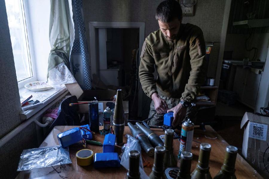 A Ukrainian soldier attaches a shell to a drone at his frontline position in Kostiantynivka. Ukraine has been retrofitting inexpensive and readily available commercial drones into effective combat weapons.