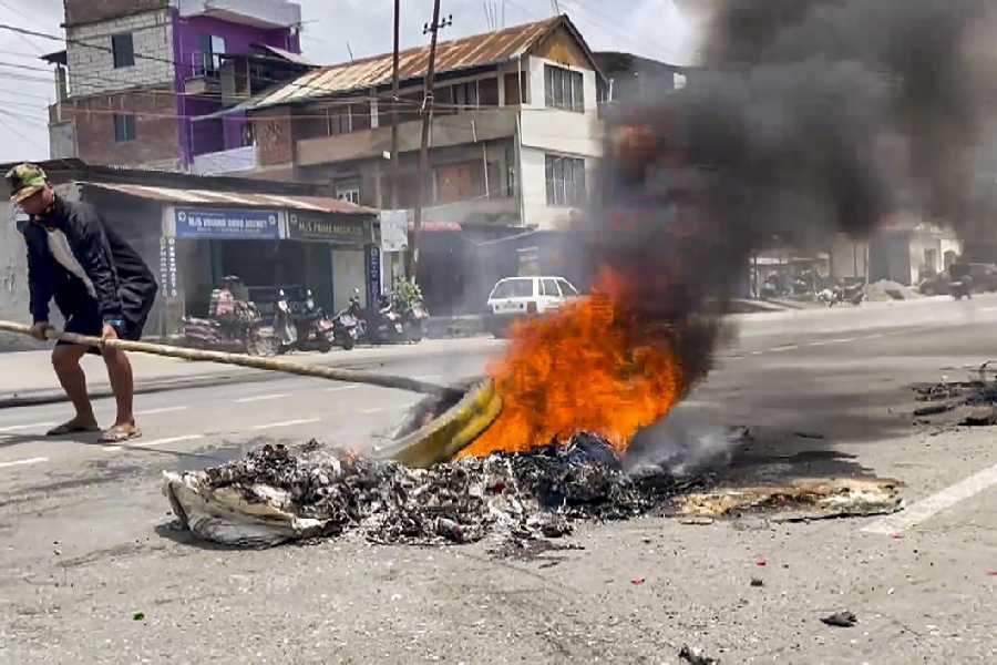 A man removes a structure from burning items after violent protests erupted in Manipur over the arrest of a leader of Meitei outfit Arambai Tenggol, in Imphal