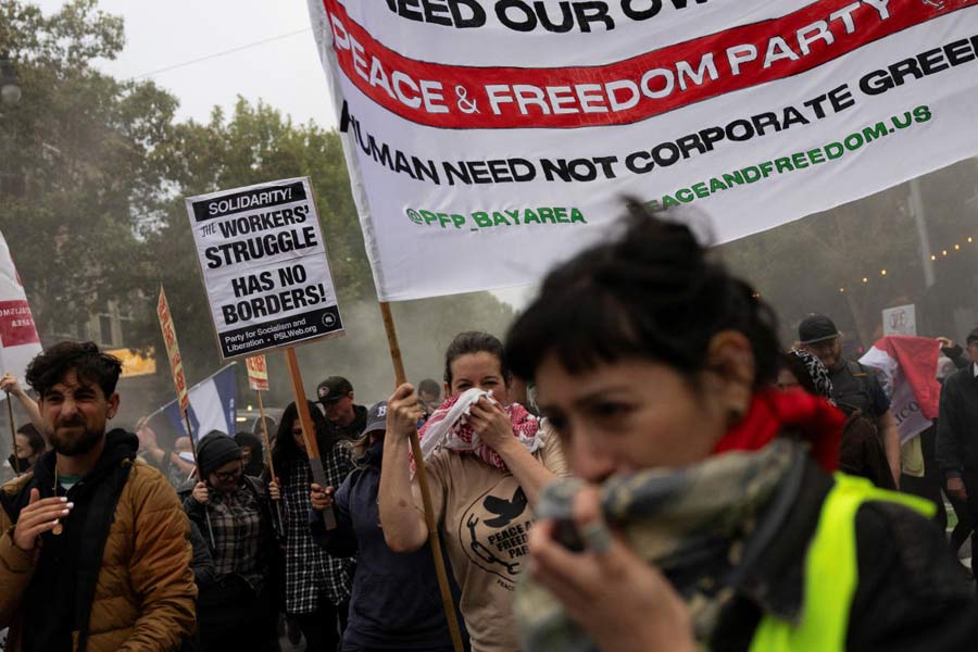 Demonstrators cover their faces from an unknown gas during a protest in the Mission District against federal immigration sweeps, in San Francisco, California, U.S.