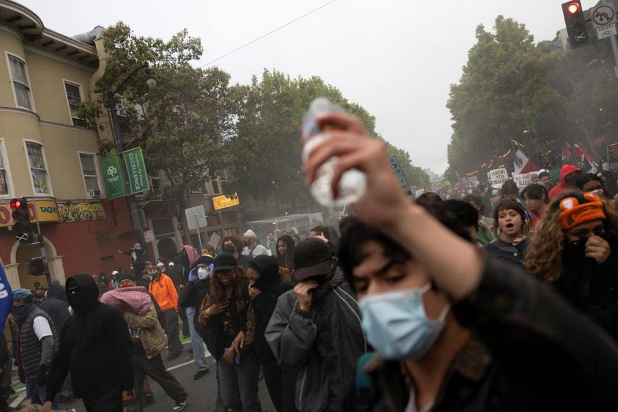 Demonstrators cover their faces from an unknown gas during a protest in the Mission District against federal immigration sweeps, in San Francisco, California, U.S.