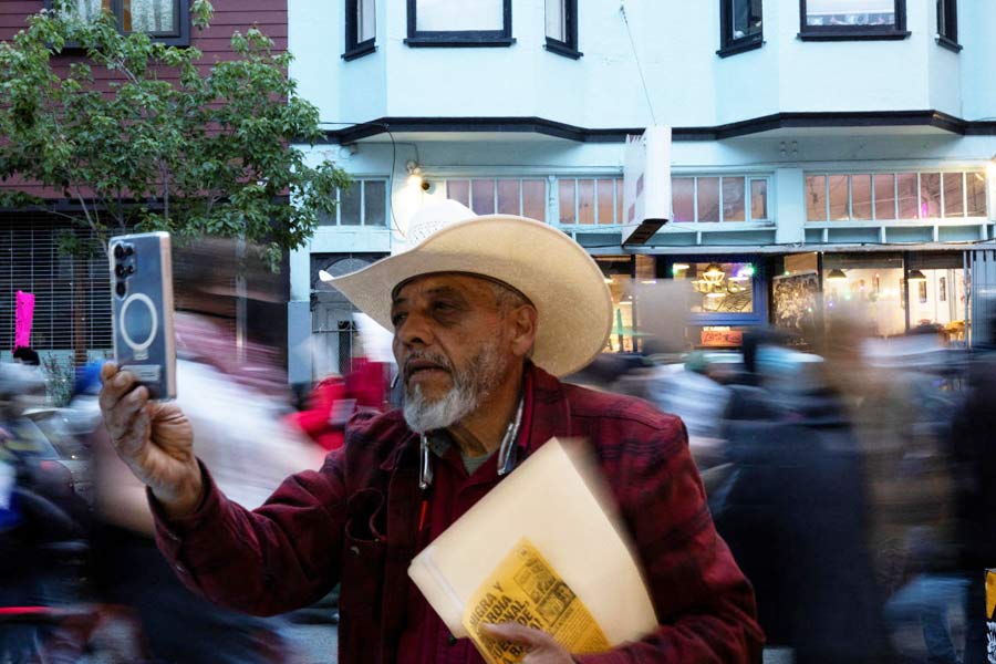 Restaurant owner Francisco Ramos uses a phone to film as demonstrators march in the Mission District during a protest against federal immigration sweeps, in San Francisco, California, U.S.