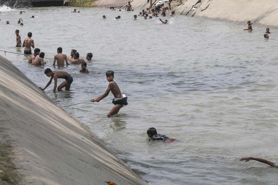 Boys bath in a canal for relief from the scorching heat, near Haiderpur Water Treatment plant in New Delhi