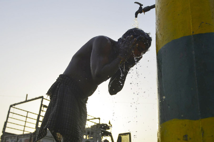 A man uses water from a roadside tap to cool off on a hot summer day, in Jalandhar