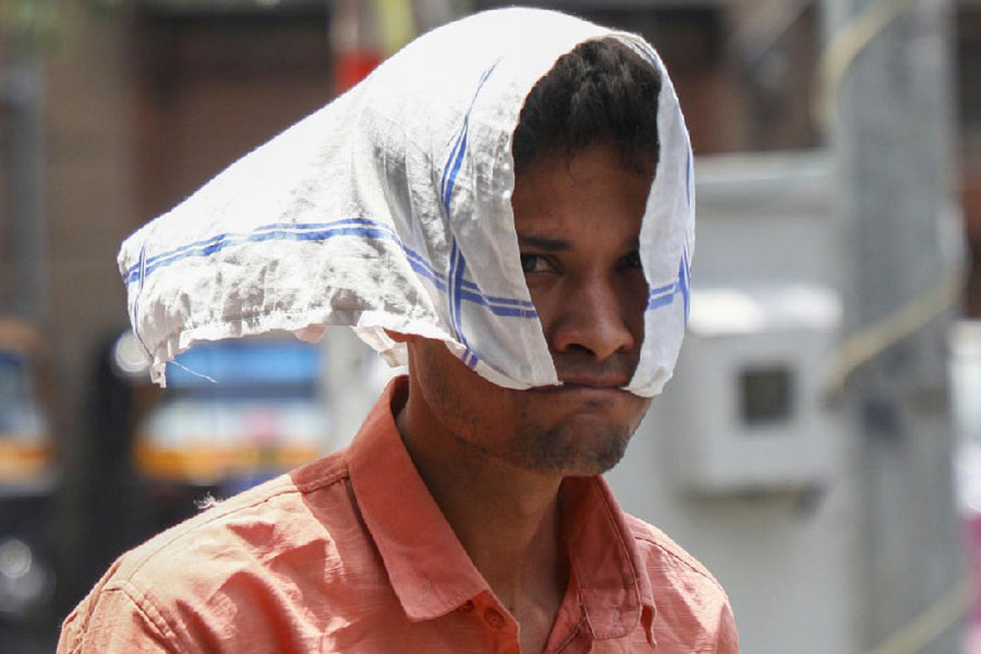 A man covers his head for protection from the scorching sun, in Jammu