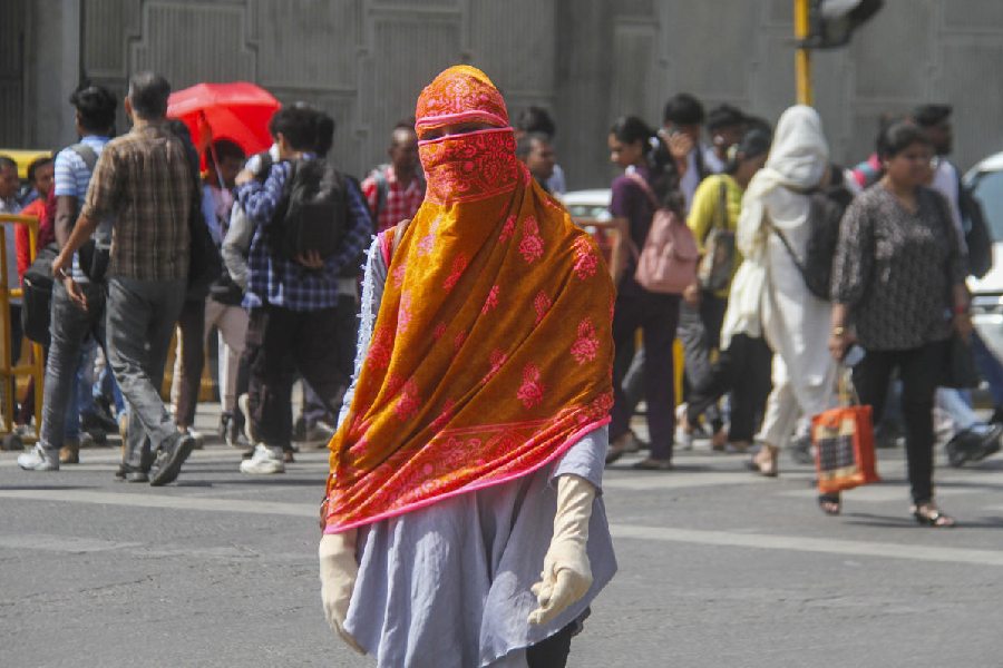 A woman uses a scarf to protect her face from the scorching sun during a summer afternoon, in Gurugram