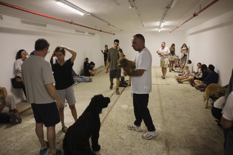 People take shelter as a siren sounds a warning following a missiles that were launched from Iran