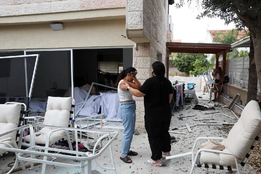 A woman reacts as she stands inside a damaged house at an impact site following missile attack