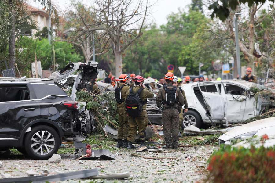 Rescue personnel stand next to damaged vehicles as they work at an impact site
