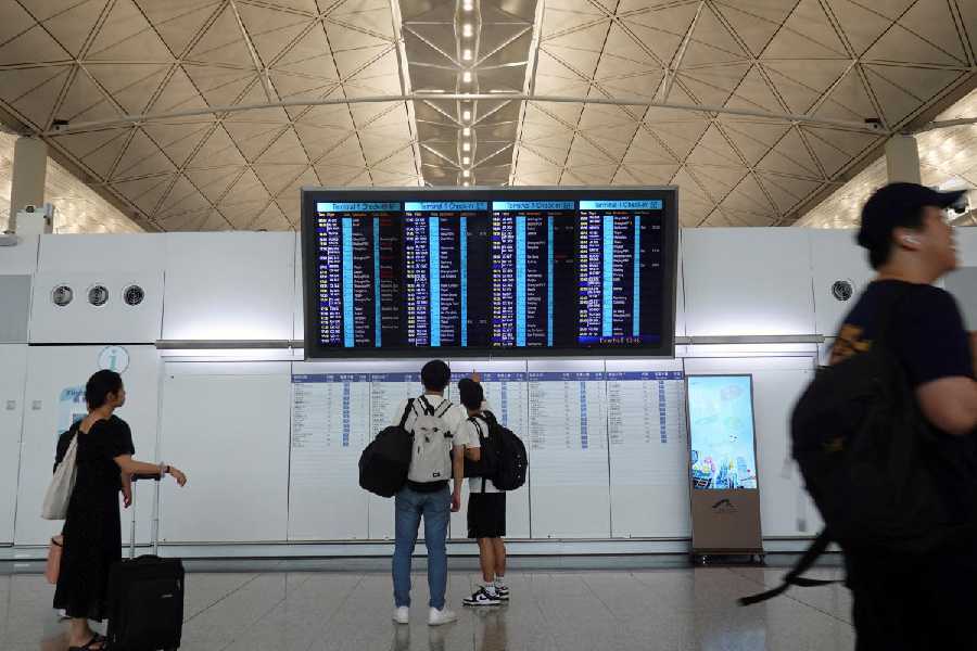 Passengers check flight information display screens at Hong Kong International Airport after flight AI315, an Air India Boeing 787-8 Dreamliner plane bound for New Delhi, returned to its origin of Hong Kong