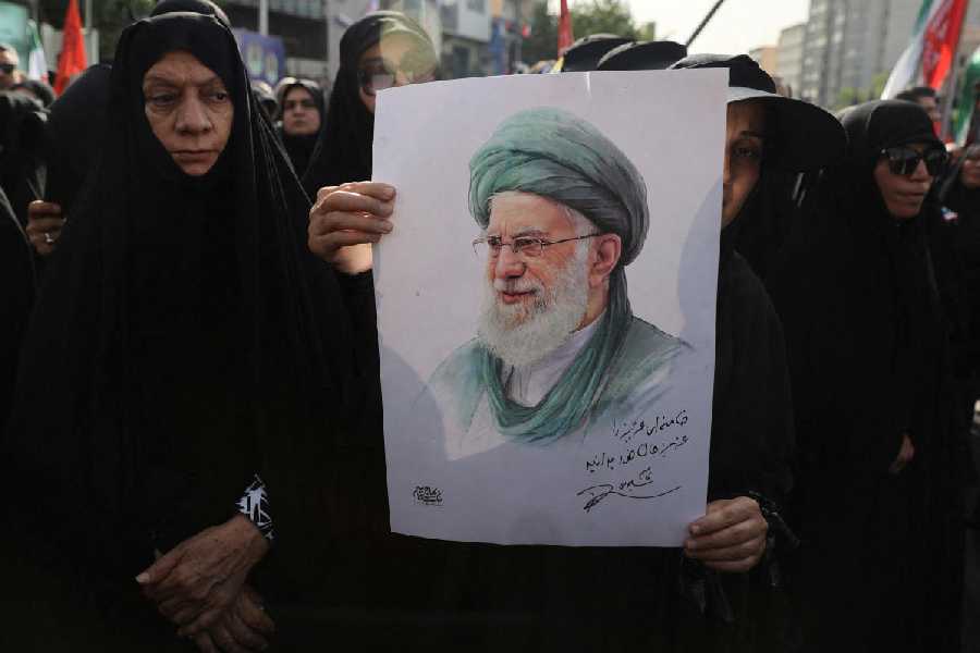 A woman holds a picture of Iran's Supreme Leader Ayatollah Ali Khamenei as she attends the funeral procession of Iranian military commanders and scientists killed in Israeli strikes, in Tehran.