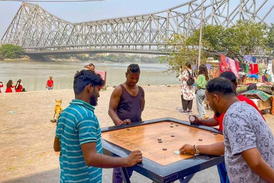 Locals enjoy a game of carrom on a lazy Sunday at Mullick Ghat, with the iconic Howrah Bridge in the backdrop  
