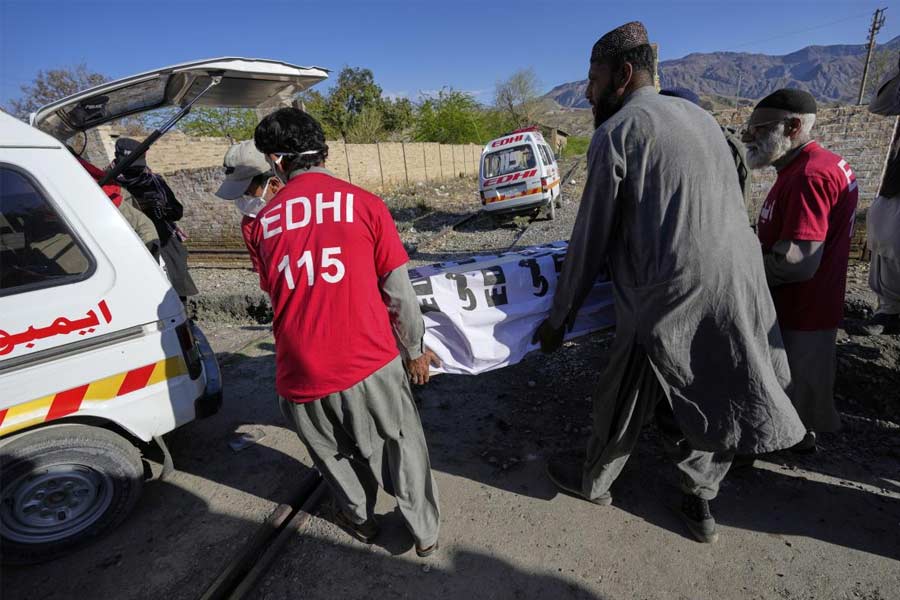 Rescue workers transport a coffin containing the body of a victim rom a passenger train attacked by insurgents, upon arrival at a railway station in Much, Pakistan's southwestern Balochistan province.