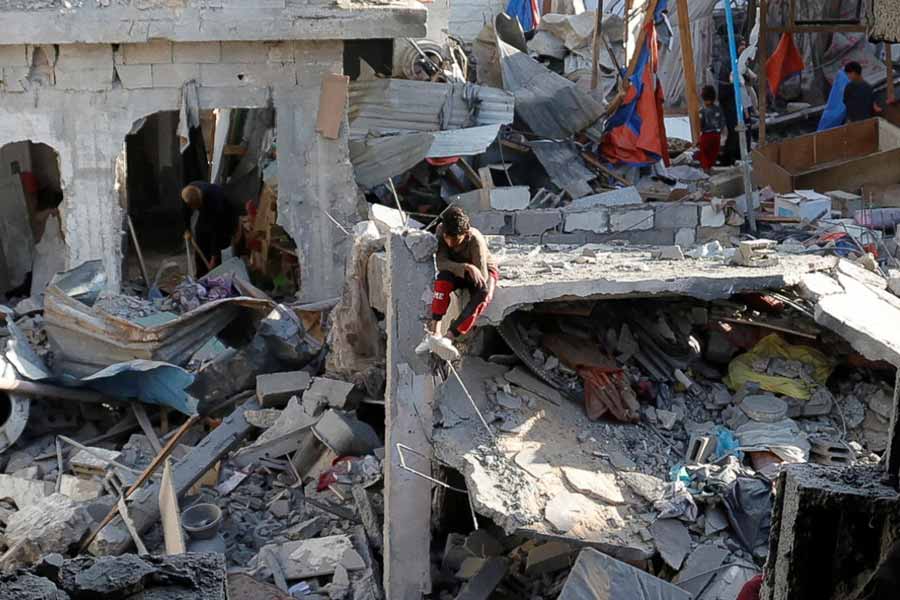 A child sits amid rubble as Palestinians inspect the site of an Israeli strike on a house, in Khan Younis in the southern Gaza Strip.