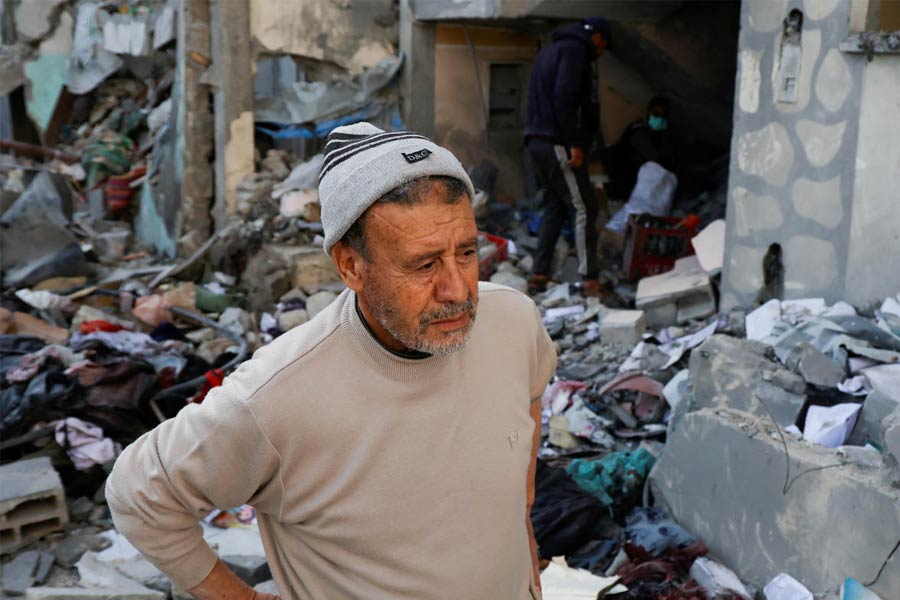 A man looks on as Palestinians inspect the site of an Israeli strike on a house, in Khan Younis in the southern Gaza Strip.