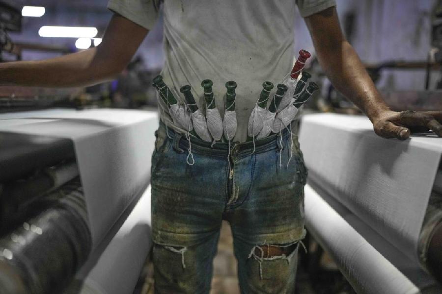 A worker keeps thread bobbins tucked in the waist of his trousers