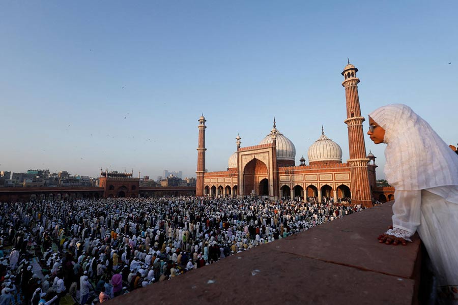 A Muslim girl watches people as they offer prayers at Jama Masjid on the occasion of Eid al-Fitr, in the old quarters of Delhi.