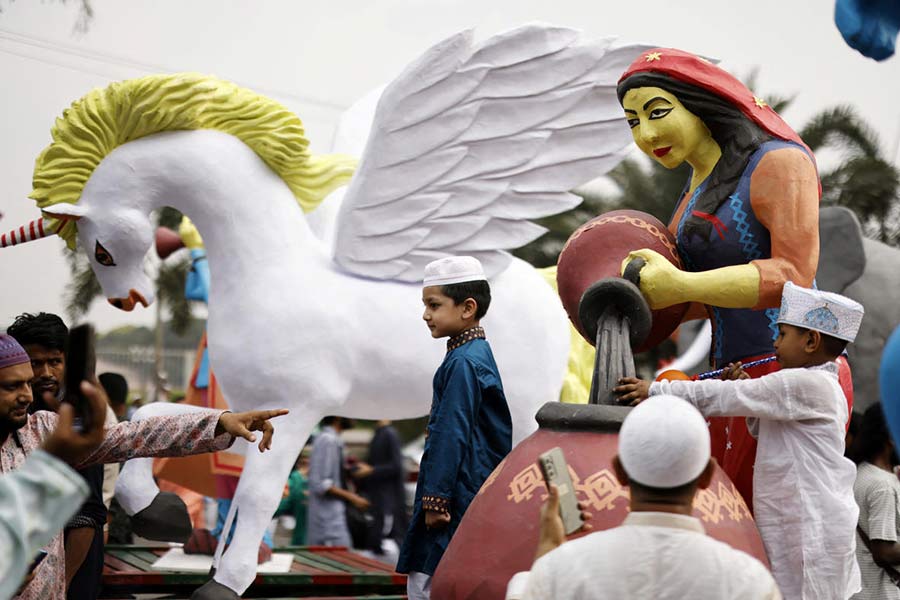 Children take pictures with makeshift sculptures brought to an Eid al-Fitr rally to mark the end of the holy month of Ramadan, in Dhaka.