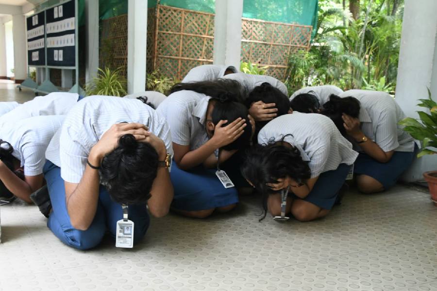 Students knelt on the ground and remained silent to simulate a secure environment. 