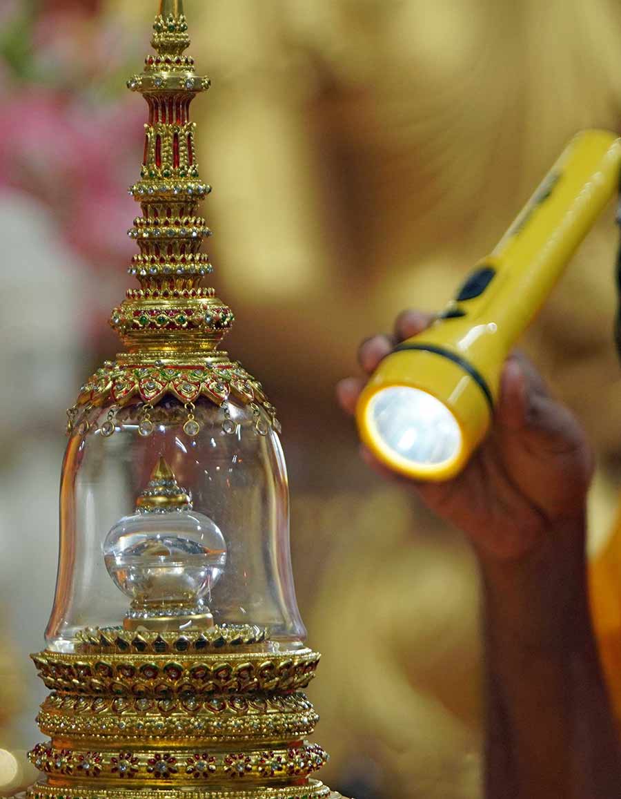 A monk shines a light on a relic casket