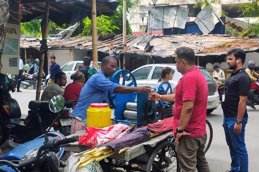 A street vendor hands over a glass of sugarcane juice to a customer in Sector V