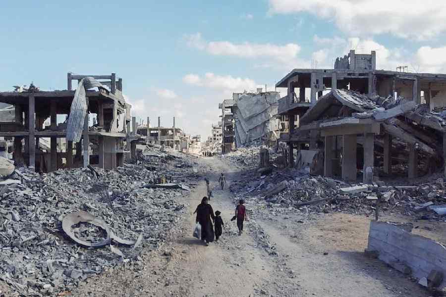 A drone view shows people walking through a destroyed residential neighbourhood in Gaza City, October 18, 2025.