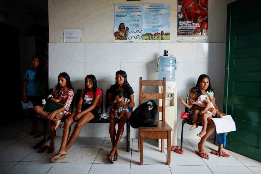 Indigenous women and children sit in a waiting room during a mission by researchers from the Brazilian public health institute Fiocruz to investigate health disorders among Munduruku Indigenous people that are potentially linked to mercury contamination caused by illegal gold mining, in Sai Cinza village, in the municipality of Jacareacanga, Para state, Brazil February 19, 2025.