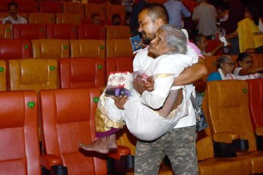 A man carrying an elderly woman leaves after watching Roi Roi Binale at a cinema hall in Guwahati on Friday.