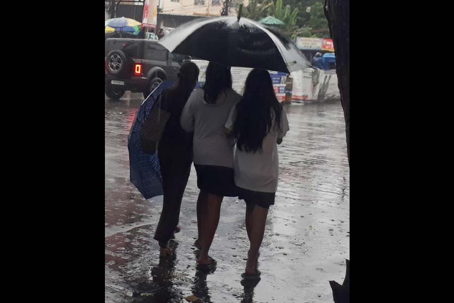 Girls share an umbrella in the rain in Siliguri on Saturday.