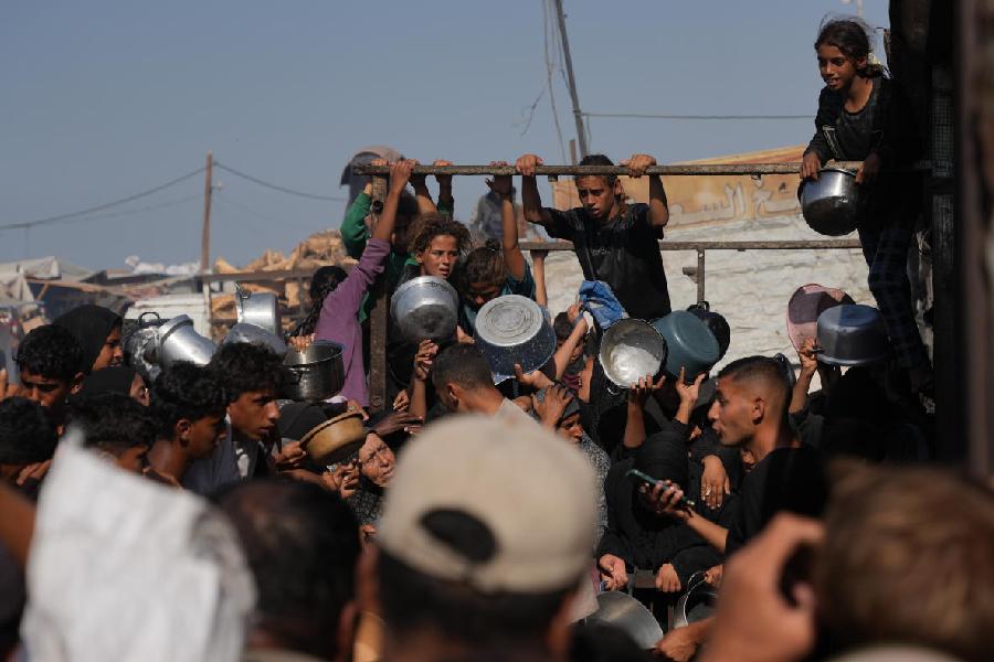 Palestinians wait to get donated sugar and rice at a community kitchen in Khan Younis, southern Gaza Strip, Friday, Oct. 31, 2025.