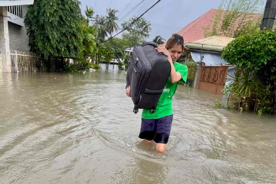 A resident navigates a flooded street as they evacuate to safer grounds as Typhoon Kalmaegi affects Cebu city, central Philippines