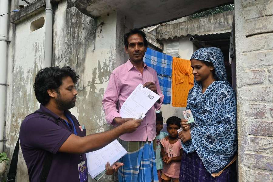 A BLO hands an enumeration form to a family at Goda in Burdwan on Tuesday.