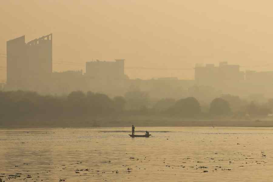 Fishermen row their boat in the Yamuna River amid low visibility on a hazy morning as the city’s air quality index falls in the poor category ahead of Diwali, at Kalindi Kunj in New Delhi.