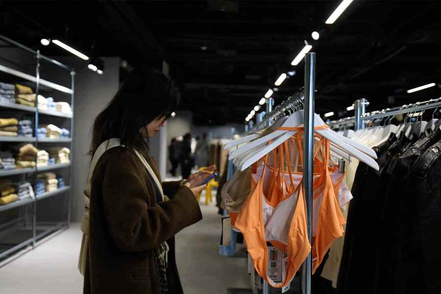 A woman looks at her mobile phone in the first physical space of Chinese online fast-fashion retailer Shein on the day of its opening inside the Le BHV Marais department store