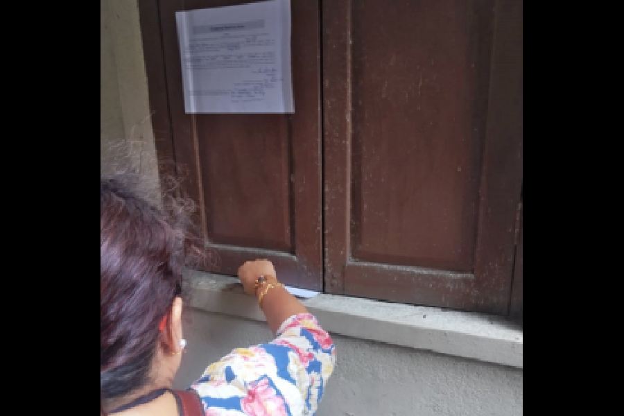 The BLO slides a form under the window of a Behala home on Wednesday