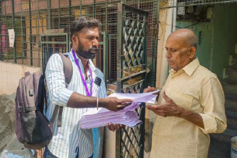 A booth-level officer gives an enumeration form to a voter as the special intensive revision of electoral rolls begins in Madurai on Tuesday. 