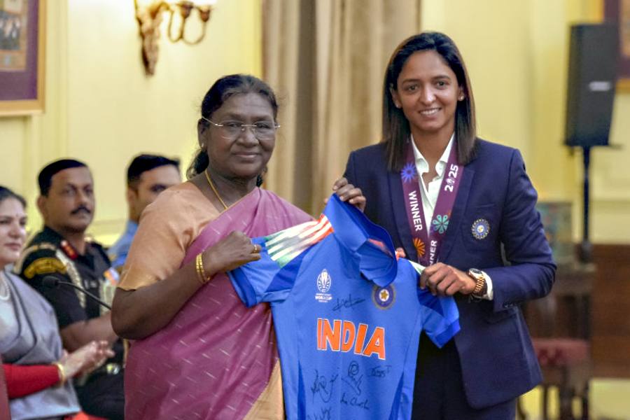 President Droupadi Murmu being presented the team's jersey by women's cricket team captain Harmanpreet Kaur