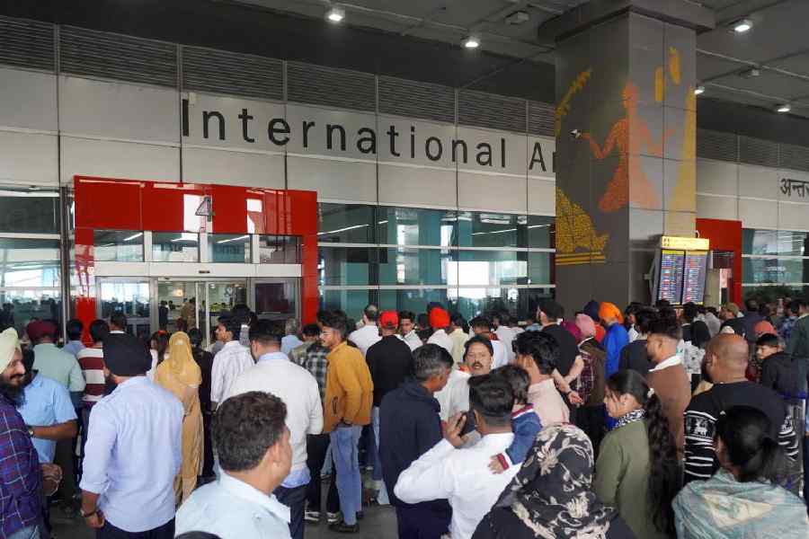 Passengers wait outside the gate of an arrival terminal at Delhi airport on Friday.