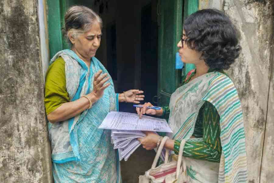 A booth-level officer (BLO) explains the details of an enumeration form to a voter for the special intensive revision of electoral rolls in Calcutta on Tuesday. (PTI)