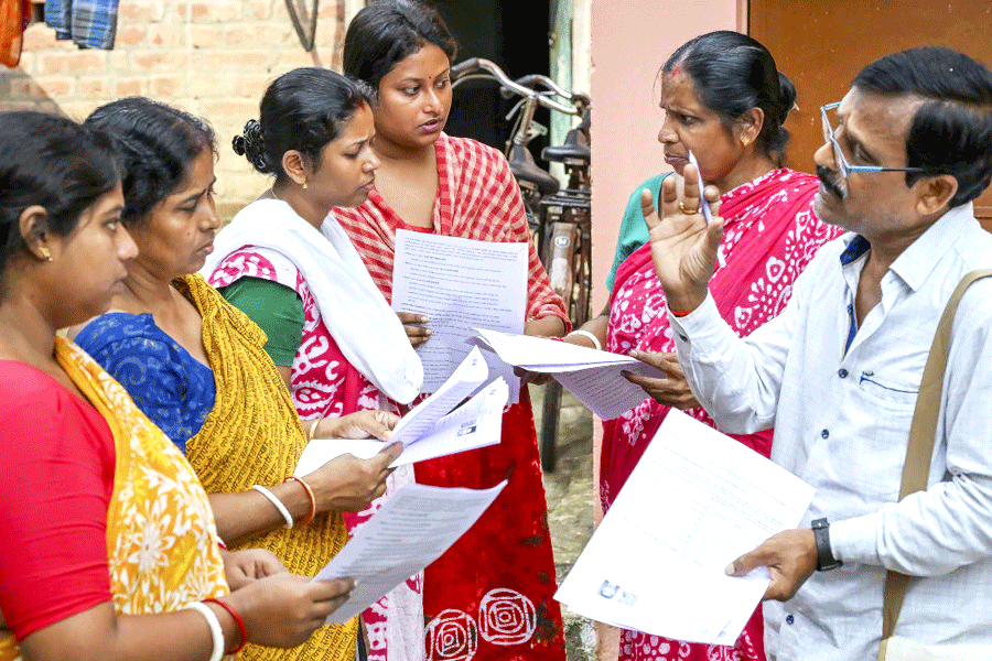 A booth level officer (BLO) explains the details of enumeration forms to voters as the SIR of electoral rolls begins in West Bengal
