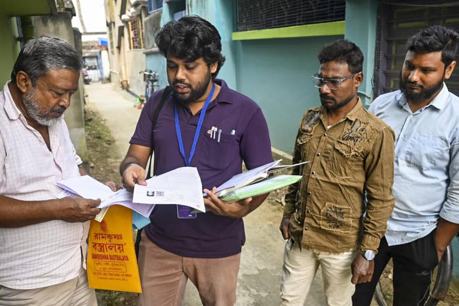 A booth level officer (BLOs) explains the details of an enumeration form to a voter as the Special Intensive Revision (SIR) of electoral rolls begins in West Bengal, in Bardhaman, West Bengal, Tuesday, Nov. 4, 2025.