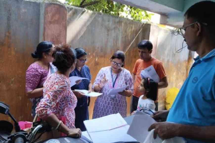 BLO Mousumi Mondal (centre) distributes enumeration forms in Ward 118 in Behala West on Saturday afternoon