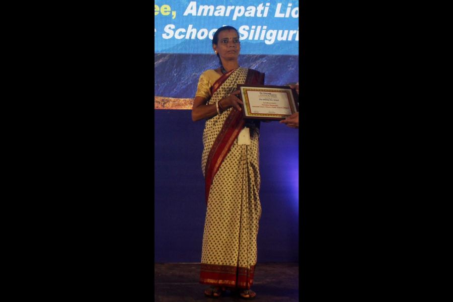 Purnima Bannerjee, an employee of Amarpati Lions Citizens Public School, Siliguri, receives her award