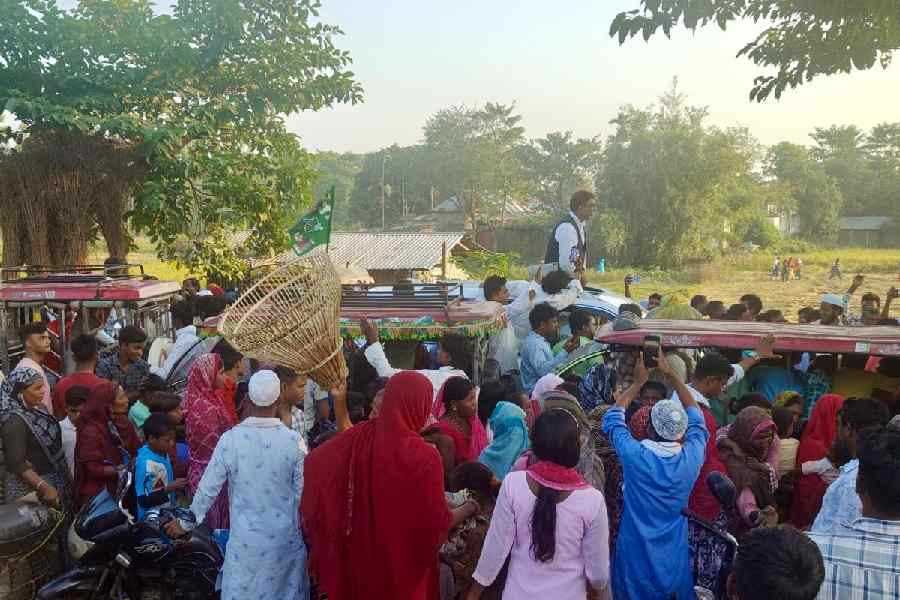 A man walks with a fish trap over his head through a roadshow of Amour AIMIM candidate Akhtarul Iman on Friday. 