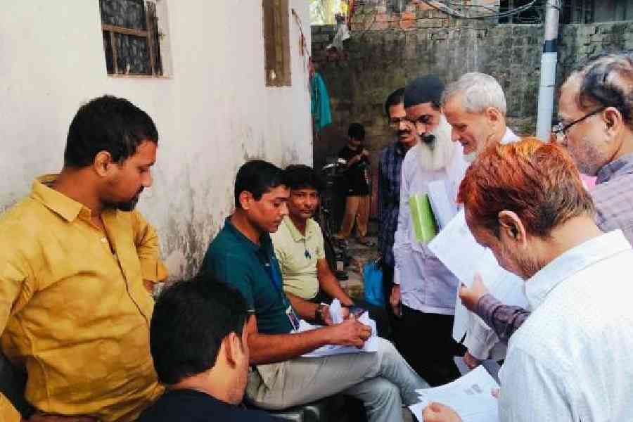 A BLO (centre) distributes enumeration forms to residents of Alimuddin Street last week