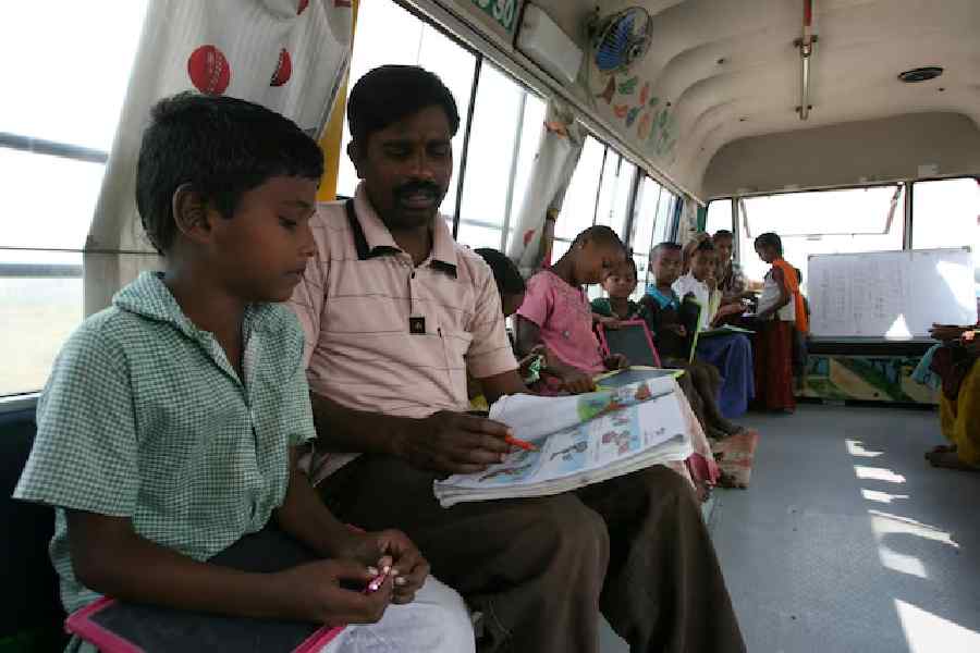 Teacher D. Laxman (2nd L) conducts lessons inside a bus which has been converted into a school called "School on Wheels" at a slum area in the southern Indian city of Hyderabad November 1, 2011.