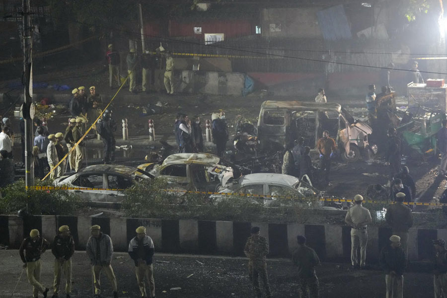 Officers from various security agencies investigate the spot after a blast occurred in a parked car near Red Fort, leaving multiple vehicles in flames, in New Delhi.