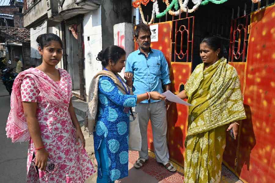 A BLO collects a filled-out enumeration form from a resident in Burdwan on Wednesday.