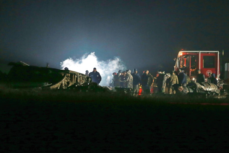 Investigators and emergency workers stand next to debris at a crash site of a Turkish military cargo plane in Georgia's Sighnaghi municipality, close to the Azerbaijani border on Wednesday, Nov. 12, 2025.