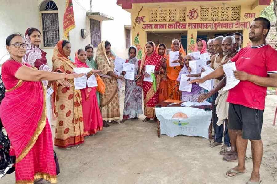 voters show the enumeration forms given by a Booth Level Officer (BLO) during the ongoing special intensive revision of electoral rolls in Bihar, in Vaishali district.